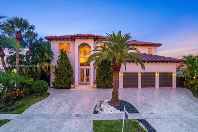 13255 Biscayne Bay Ter, North Miami, FL 33181 - mediterranean / spanish home with curved driveway, an attached garage, stucco siding, and a tiled roof