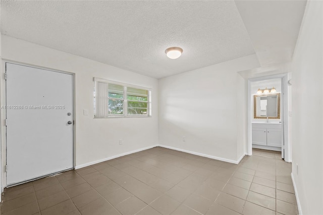 3253 Foxcroft Rd Unit G312, Miramar, FL 33025 - tiled spare room with a textured ceiling, baseboards, and a sink