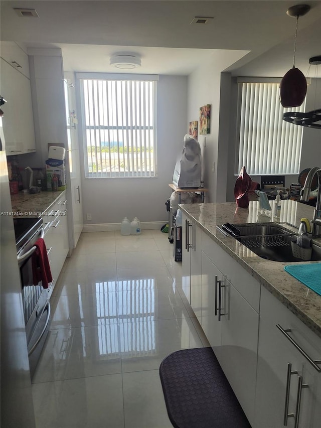 4330 Hillcrest Dr Unit 619, Hollywood, FL 33021 - kitchen with stove, light tile patterned floors, light stone countertops, white cabinetry, and hanging light fixtures