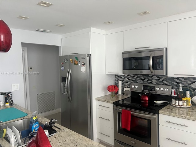 4330 Hillcrest Dr Unit 619, Hollywood, FL 33021 - kitchen featuring appliances with stainless steel finishes, white cabinetry, backsplash, light stone counters, and modern cabinets