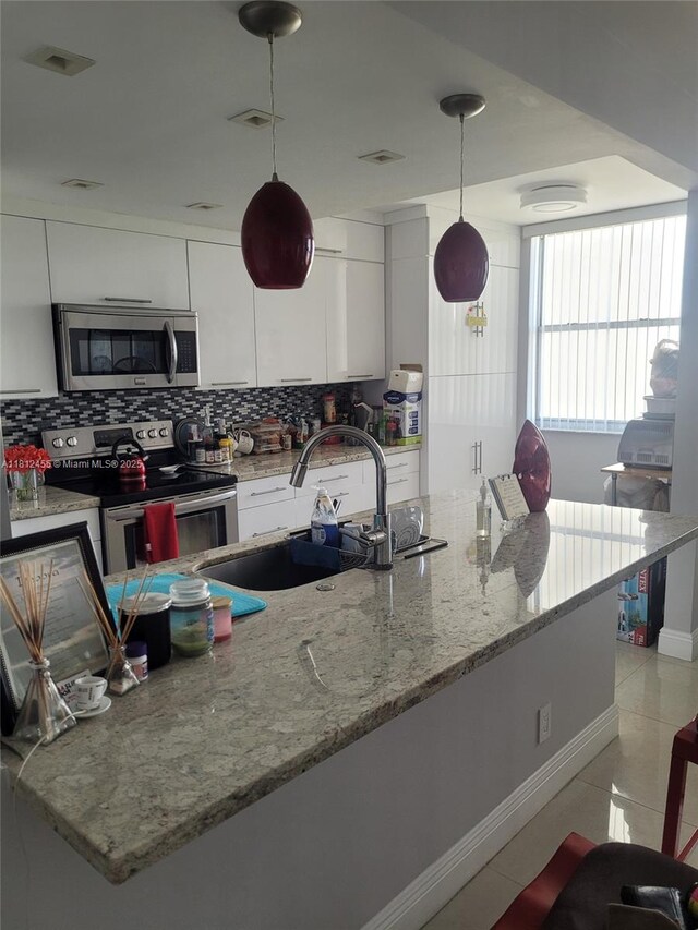 4330 Hillcrest Dr Unit 619, Hollywood, FL 33021 - kitchen with appliances with stainless steel finishes, tasteful backsplash, white cabinets, and decorative light fixtures