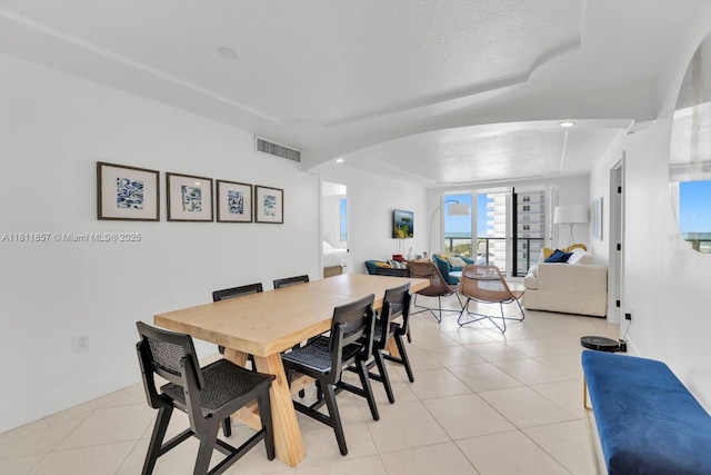 5701 Collins Ave Unit 712, Miami Beach, FL 33140 - dining room with light tile patterned flooring, a tray ceiling, arched walkways, and baseboards