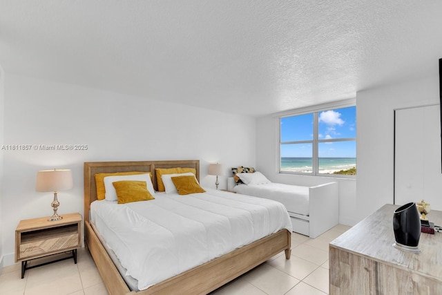 5701 Collins Ave Unit 712, Miami Beach, FL 33140 - bedroom featuring light tile patterned floors, a water view, and a textured ceiling