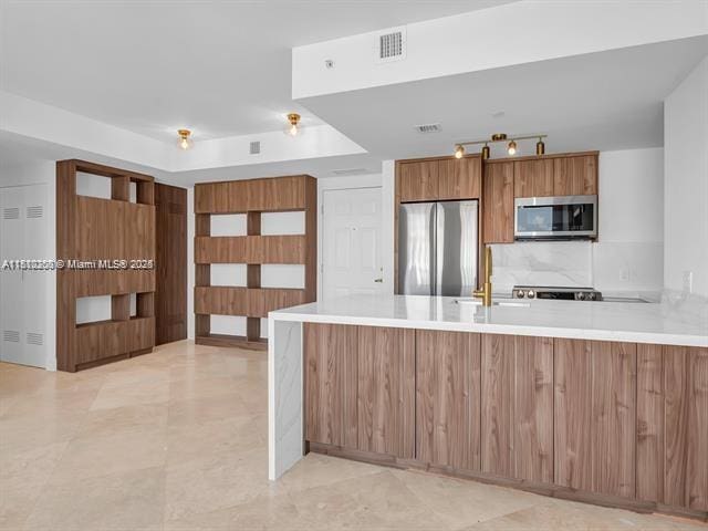 4100 Salzedo St Unit 901, Coral Gables, FL 33146 - kitchen featuring stainless steel appliances, a peninsula, light countertops, brown cabinets, and modern cabinets