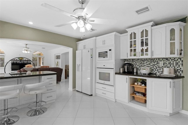 10421 NW 21st St, Pembroke Pines, FL 33026 - kitchen featuring white appliances, dark countertops, ceiling fan, arched walkways, and glass insert cabinets
