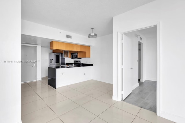 1750 N Bayshore Dr Unit 4801, Miami, FL 33132 - kitchen with appliances with stainless steel finishes, dark countertops, a peninsula, brown cabinets, and light tile patterned floors
