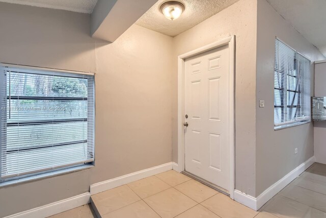7521 Granada Blvd, Miramar, FL 33023 - entryway with light tile patterned floors, healthy amount of natural light, baseboards, and a textured ceiling
