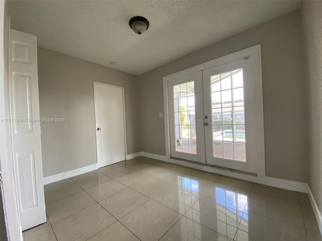 7521 Granada Blvd, Miramar, FL 33023 - spare room featuring baseboards, a textured ceiling, light tile patterned flooring, and french doors