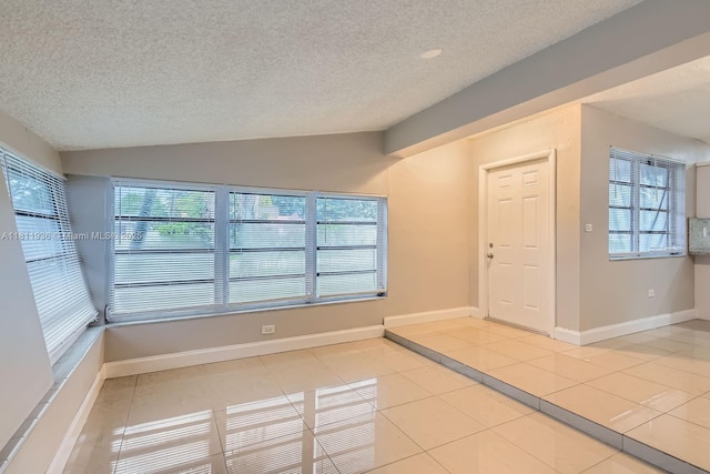 7521 Granada Blvd, Miramar, FL 33023 - empty room featuring a textured ceiling, vaulted ceiling, plenty of natural light, light tile patterned floors, and baseboards
