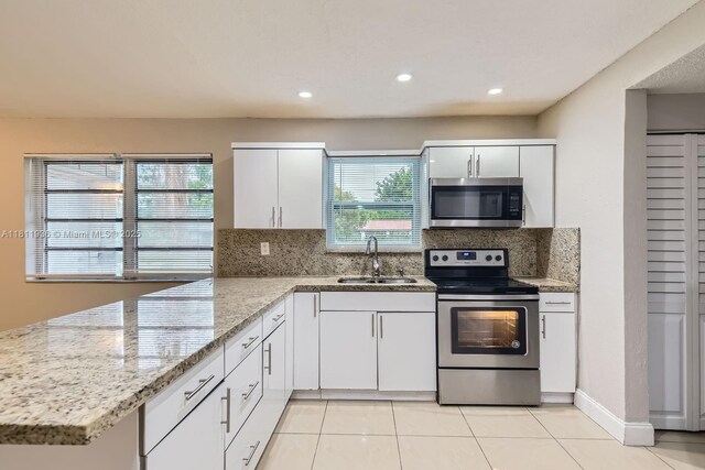 7521 Granada Blvd, Miramar, FL 33023 - kitchen with stainless steel appliances, a sink, a peninsula, decorative backsplash, and light tile patterned floors