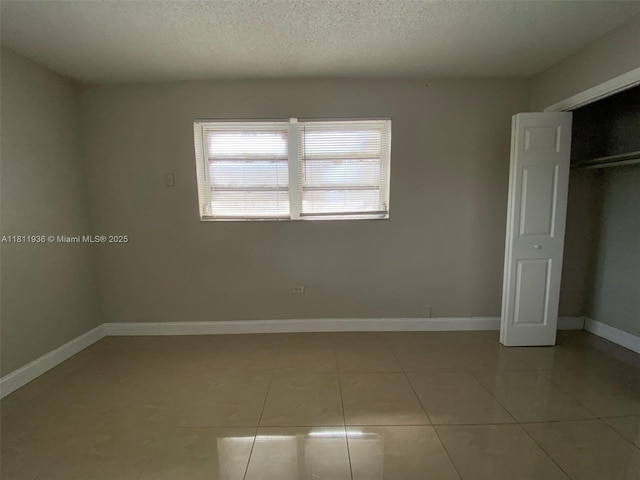 7521 Granada Blvd, Miramar, FL 33023 - unfurnished bedroom featuring light tile patterned flooring, baseboards, a textured ceiling, and a closet