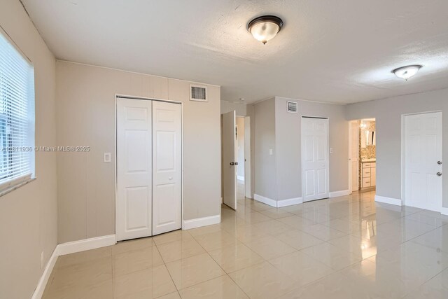 7521 Granada Blvd, Miramar, FL 33023 - unfurnished bedroom with two closets, light tile patterned flooring, baseboards, and a textured ceiling