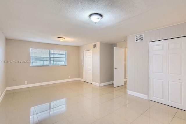 7521 Granada Blvd, Miramar, FL 33023 - unfurnished bedroom with baseboards, a textured ceiling, two closets, and light tile patterned flooring