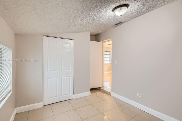 7521 Granada Blvd, Miramar, FL 33023 - unfurnished bedroom with light tile patterned flooring, a closet, a textured ceiling, and baseboards