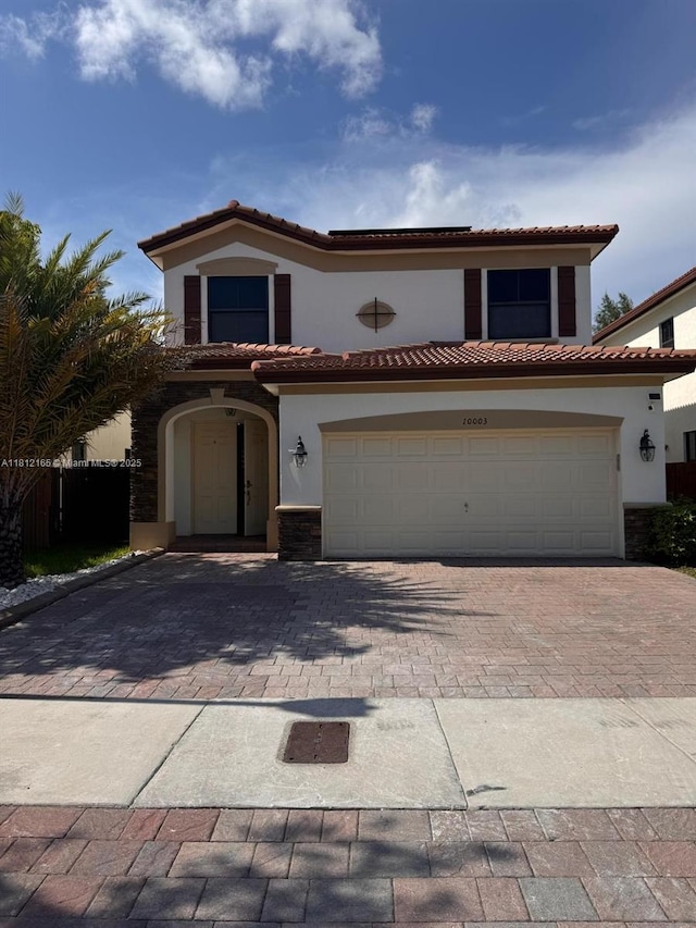 10003 NW 89th Ter, Doral, FL 33178 - mediterranean / spanish-style home featuring stucco siding, decorative driveway, a garage, a tile roof, and stone siding