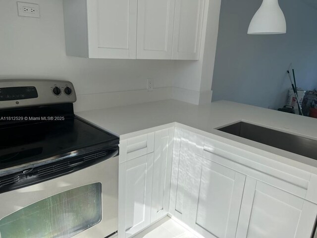 5200 NW 31st Ave Unit 14, Fort Lauderdale, FL 33309 - kitchen featuring electric range, light countertops, and white cabinets