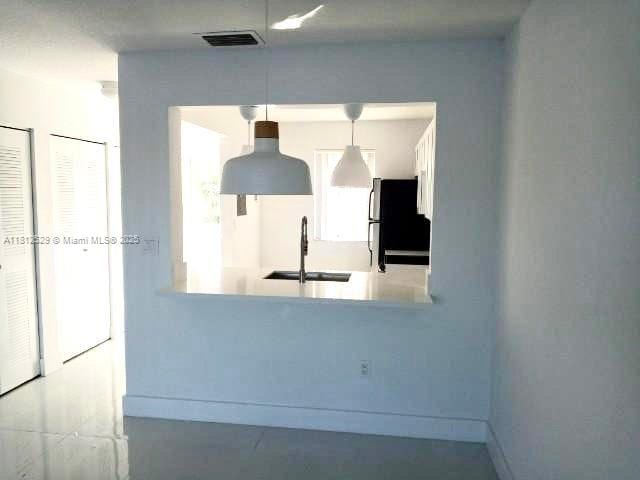5200 NW 31st Ave Unit 14, Fort Lauderdale, FL 33309 - kitchen featuring freestanding refrigerator, a sink, baseboards, and hanging light fixtures