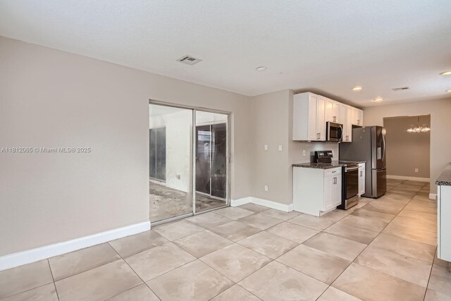9353 SW 1st Pl, Boca Raton, FL 33428 - kitchen featuring appliances with stainless steel finishes, white cabinetry, dark stone counters, light tile patterned floors, and baseboards