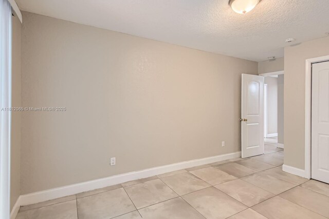 9353 SW 1st Pl, Boca Raton, FL 33428 - unfurnished bedroom featuring light tile patterned floors, a closet, a textured ceiling, and baseboards