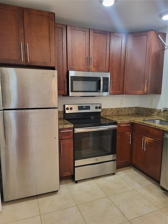 340 84th St Unit 2, Miami Beach, FL 33141 - kitchen featuring appliances with stainless steel finishes, a sink, light tile patterned flooring, and dark stone counters