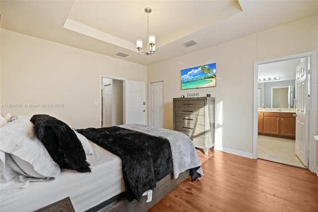 23900 SW 118th Ave, Homestead, FL 33032 - bedroom with light wood finished floors, a raised ceiling, a chandelier, and connected bathroom