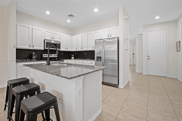 659 NE 191st St, Miami, FL 33179 - kitchen featuring appliances with stainless steel finishes, dark stone countertops, a kitchen breakfast bar, tasteful backsplash, and light tile patterned floors