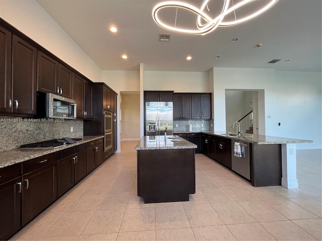 8248 Lost Creek Ln, Delray Beach, FL 33446 - kitchen featuring appliances with stainless steel finishes, a sink, tasteful backsplash, an island with sink, and light stone countertops