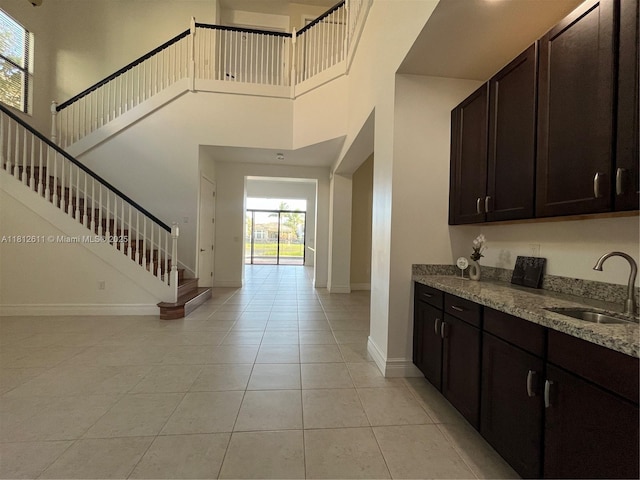 8248 Lost Creek Ln, Delray Beach, FL 33446 - kitchen featuring a sink, a high ceiling, light stone countertops, baseboards, and light tile patterned flooring