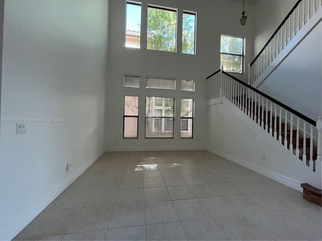8248 Lost Creek Ln, Delray Beach, FL 33446 - unfurnished living room with a towering ceiling, tile patterned flooring, baseboards, and stairs