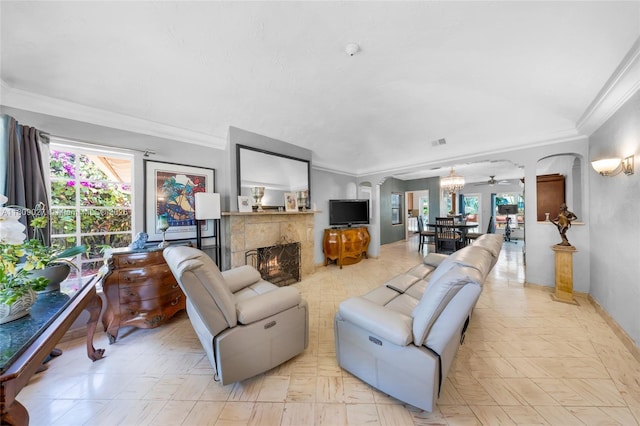 703 NE 88th St, Miami, FL 33138 - living area with ornamental molding, arched walkways, a lit fireplace, a chandelier, and decorative columns