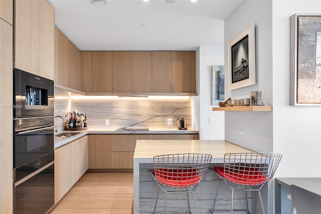 8701 Collins Ave Unit 905, Miami Beach, FL 33154 - kitchen featuring modern cabinets, backsplash, light countertops, light wood finished floors, and recessed lighting