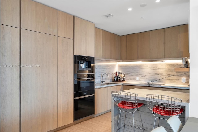 8701 Collins Ave Unit 905, Miami Beach, FL 33154 - kitchen featuring a sink, light wood-style flooring, modern cabinets, light brown cabinetry, and recessed lighting