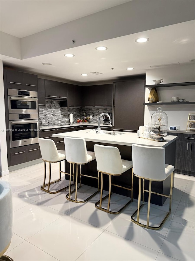 7661 NW 107th Ave Unit 303, Doral, FL 33178 - kitchen featuring a kitchen bar, tasteful backsplash, a center island with sink, stainless steel double oven, and recessed lighting