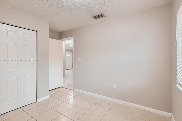 20316 NW 32nd Path, Miami Gardens, FL 33056 - unfurnished bedroom with a closet, baseboards, light tile patterned floors, and a textured ceiling