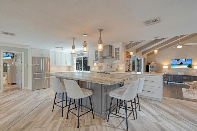 2750 SW 86th Way, Davie, FL 33328 - kitchen with freestanding refrigerator, a peninsula, wall chimney exhaust hood, a kitchen island, and white cabinetry