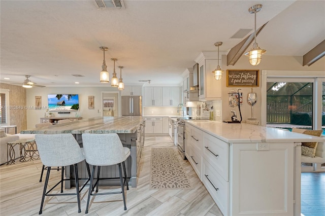 2750 SW 86th Way, Davie, FL 33328 - kitchen featuring stainless steel appliances, open floor plan, a breakfast bar, white cabinetry, and a sink