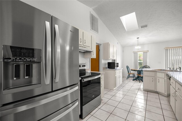 2521 NW 45th, Ocala, FL 34475 - kitchen featuring stainless steel appliances, vaulted ceiling, a skylight, under cabinet range hood, and decorative light fixtures
