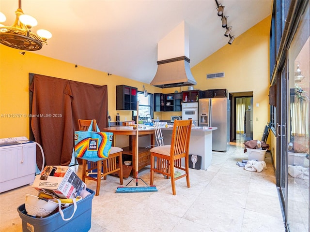802 SE Kendall Ave, Port St Lucie, FL 34983 - kitchen with stainless steel fridge, a chandelier, track lighting, high vaulted ceiling, and a peninsula