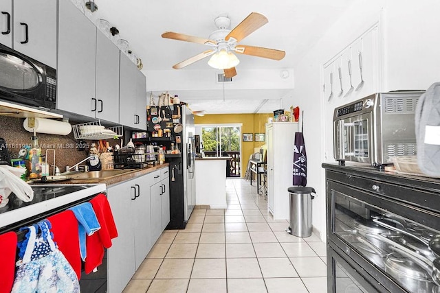911 E 9th Pl, Hialeah, FL 33010 - kitchen featuring black microwave, ceiling fan, decorative backsplash, light tile patterned flooring, and stainless steel refrigerator with ice dispenser