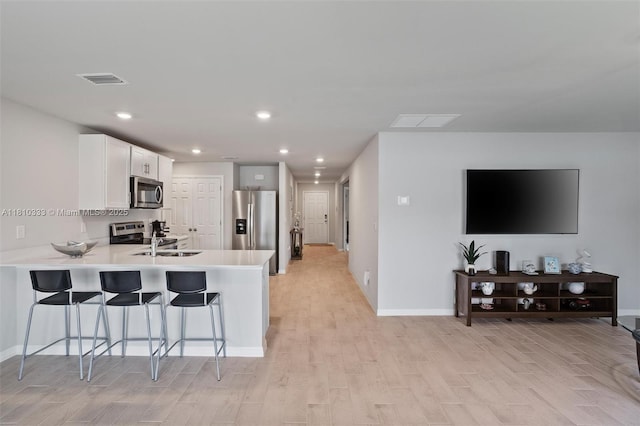 3021 June Cir Fl, LaBelle, FL 33935 - kitchen with stainless steel appliances, light wood-style flooring, a peninsula, a kitchen breakfast bar, and light countertops