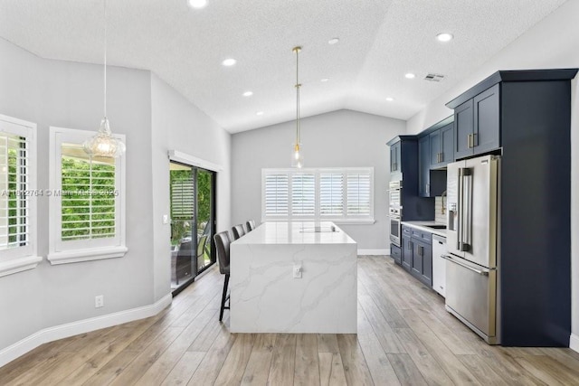 20141 NW 8th St, Pembroke Pines, FL 33029 - kitchen featuring appliances with stainless steel finishes, vaulted ceiling, light wood-style floors, light stone countertops, and a kitchen island
