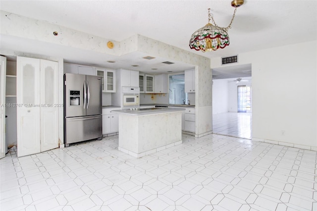 1006 NE 24th Ave Unit 190, Hallandale Beach, FL 33009 - kitchen featuring stainless steel fridge, white oven, glass insert cabinets, white cabinets, and a kitchen island