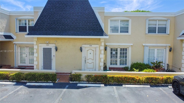 1006 NE 24th Ave Unit 190, Hallandale Beach, FL 33009 - view of property with french doors, stucco siding, uncovered parking, and a shingled roof