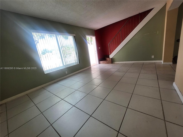 1061 NW 80th Ave Unit J, Margate, FL 33063 - unfurnished living room with a textured ceiling, tile patterned flooring, and stairs