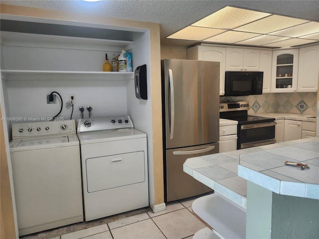 1061 NW 80th Ave Unit J, Margate, FL 33063 - kitchen with stainless steel appliances, tile countertops, washing machine and dryer, and white cabinets