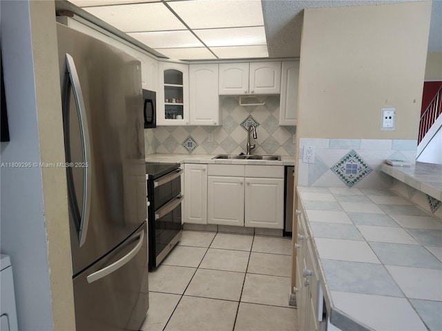 1061 NW 80th Ave Unit J, Margate, FL 33063 - kitchen featuring stainless steel appliances, tile countertops, white cabinetry, tasteful backsplash, and light tile patterned floors