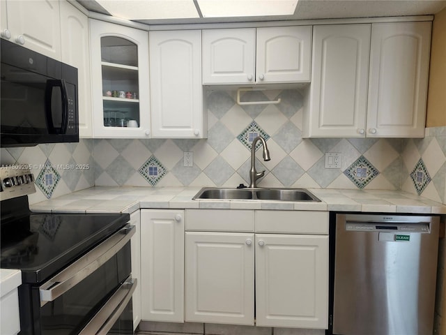 1061 NW 80th Ave Unit J, Margate, FL 33063 - kitchen featuring appliances with stainless steel finishes, glass insert cabinets, white cabinetry, tasteful backsplash, and tile countertops
