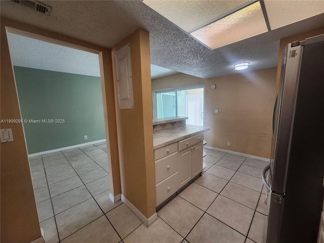 1061 NW 80th Ave Unit J, Margate, FL 33063 - kitchen featuring freestanding refrigerator, tile counters, white cabinets, light tile patterned floors, and a textured ceiling