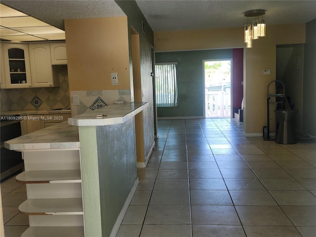 1061 NW 80th Ave Unit J, Margate, FL 33063 - kitchen with tile countertops, open shelves, decorative backsplash, light tile patterned floors, and white cabinets