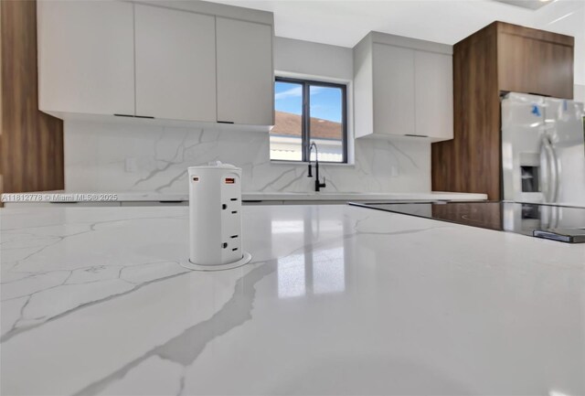 2411 NW 153rd St, Miami Gardens, FL 33054 - kitchen featuring stainless steel fridge with ice dispenser, decorative backsplash, light stone countertops, modern cabinets, and a sink